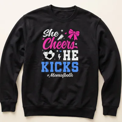 Colorful shirt with text 'She Cheers He Kicks #Momofboth' and graphics of pom-poms and a soccer ball — printed on a unisex sweatshirt