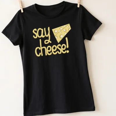 Playful cartoon cheese with text 'say cheese!' in yellow tones — printed on a women's shirt