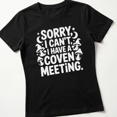Playful graphic featuring the text 'Sorry I Can’t I Have A Coven Meeting' in black, white, and purple — printed on a women's shirt