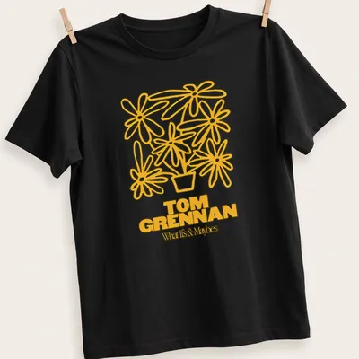 Line art illustration of a flower pot with flowers and text 'TOM GRENNAN What Is & Maybes'