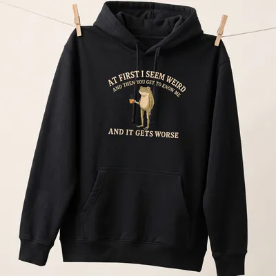 Whimsical illustration of a frog holding a coffee mug with funny text — printed on a unisex hoodie