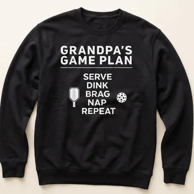 Bold typography design with the phrase Grandpa's Game Plan Serve Dink Brag Nap Repeat — printed on a unisex sweatshirt