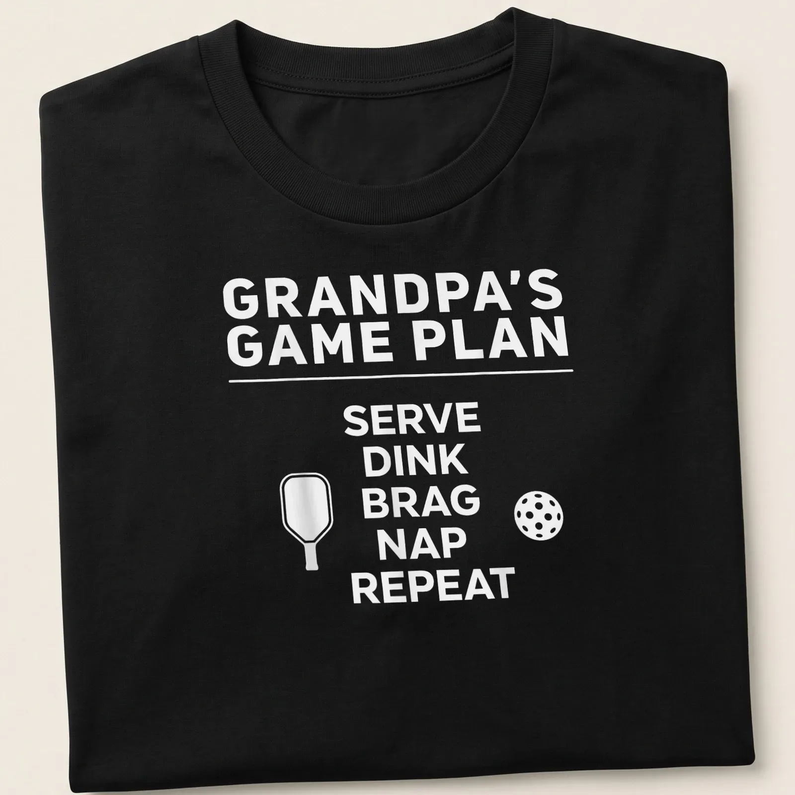 Bold typography design with the phrase Grandpa's Game Plan Serve Dink Brag Nap Repeat — printed on a unisex t-shirt