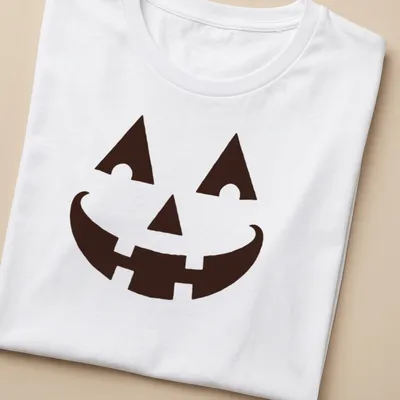 Simple graphic of a happy pumpkin face on a black t-shirt for Halloween — printed on a women's shirt