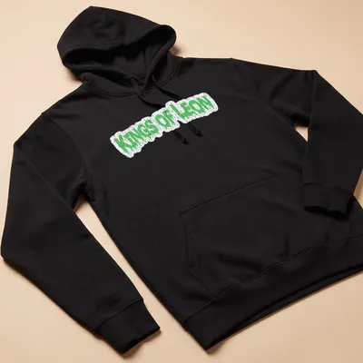 Grunge-style Kings Of Leon t-shirt with green dripping text design — printed on a unisex hoodie