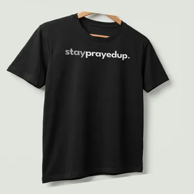 Minimalist design featuring the phrase stay prayed up in white and gray — printed on a unisex t-shirt (angled view)