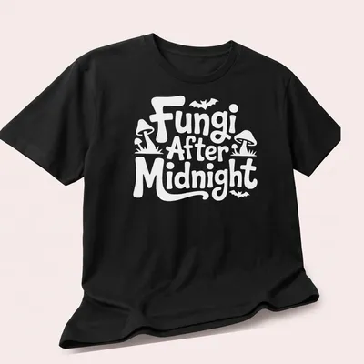 Whimsical illustration of mushrooms with 'Fungi After Midnight' text in purple, green, and blue. — printed on a unisex t-shirt (angled view)