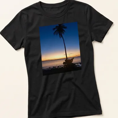 Silhouette of a palm tree against a colorful sunset horizon. — printed on a women's shirt