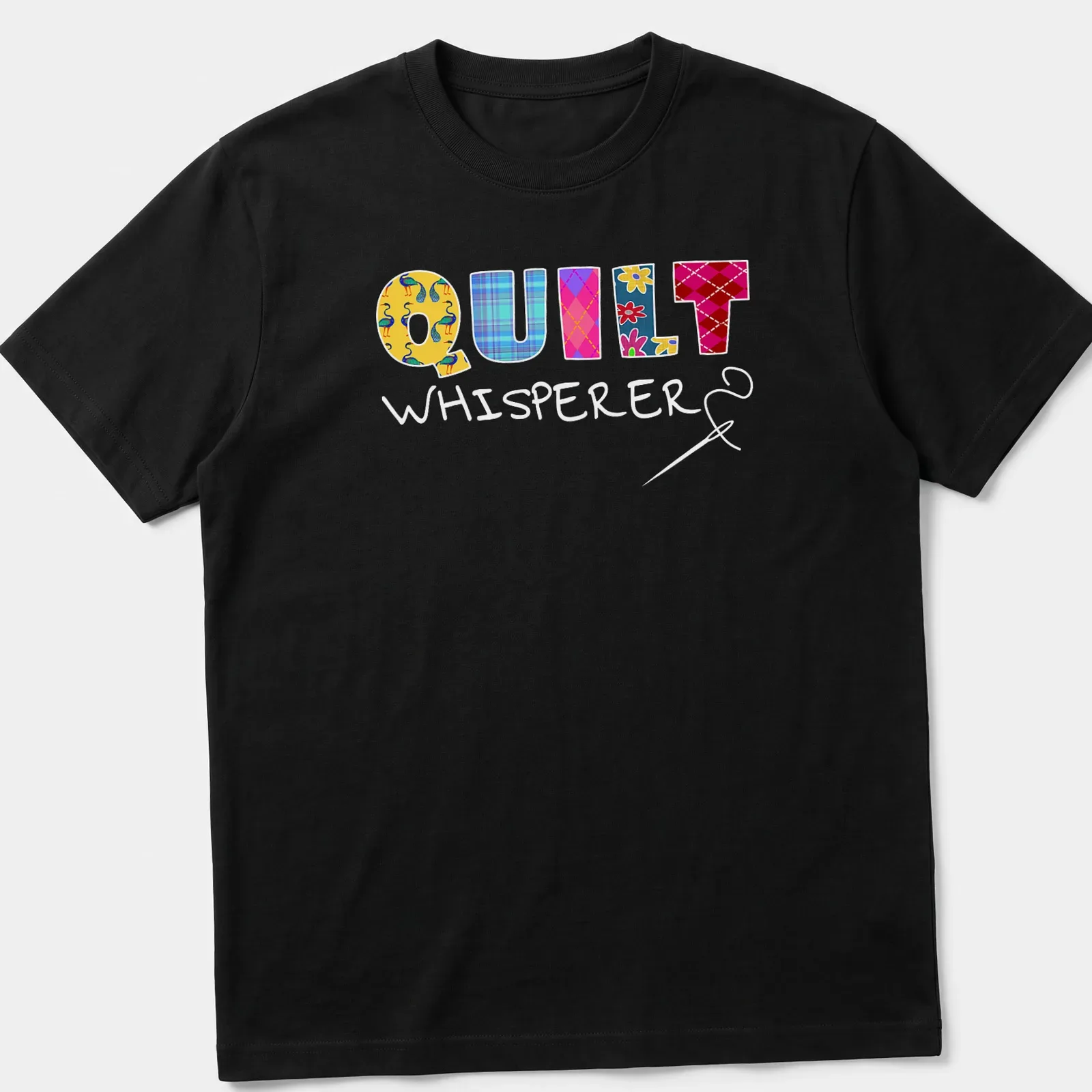 Colorful patchwork design with floral patterns spelling Quilt Whisperer — printed on a unisex t-shirt