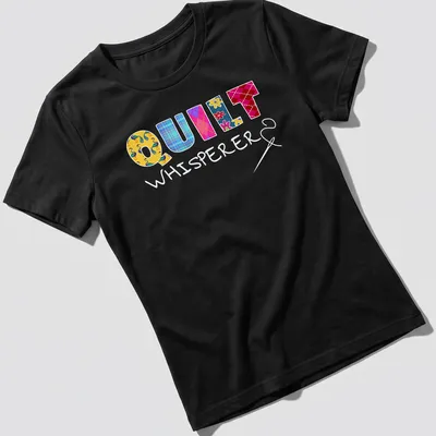 Colorful patchwork design with floral patterns spelling Quilt Whisperer — printed on a women's shirt