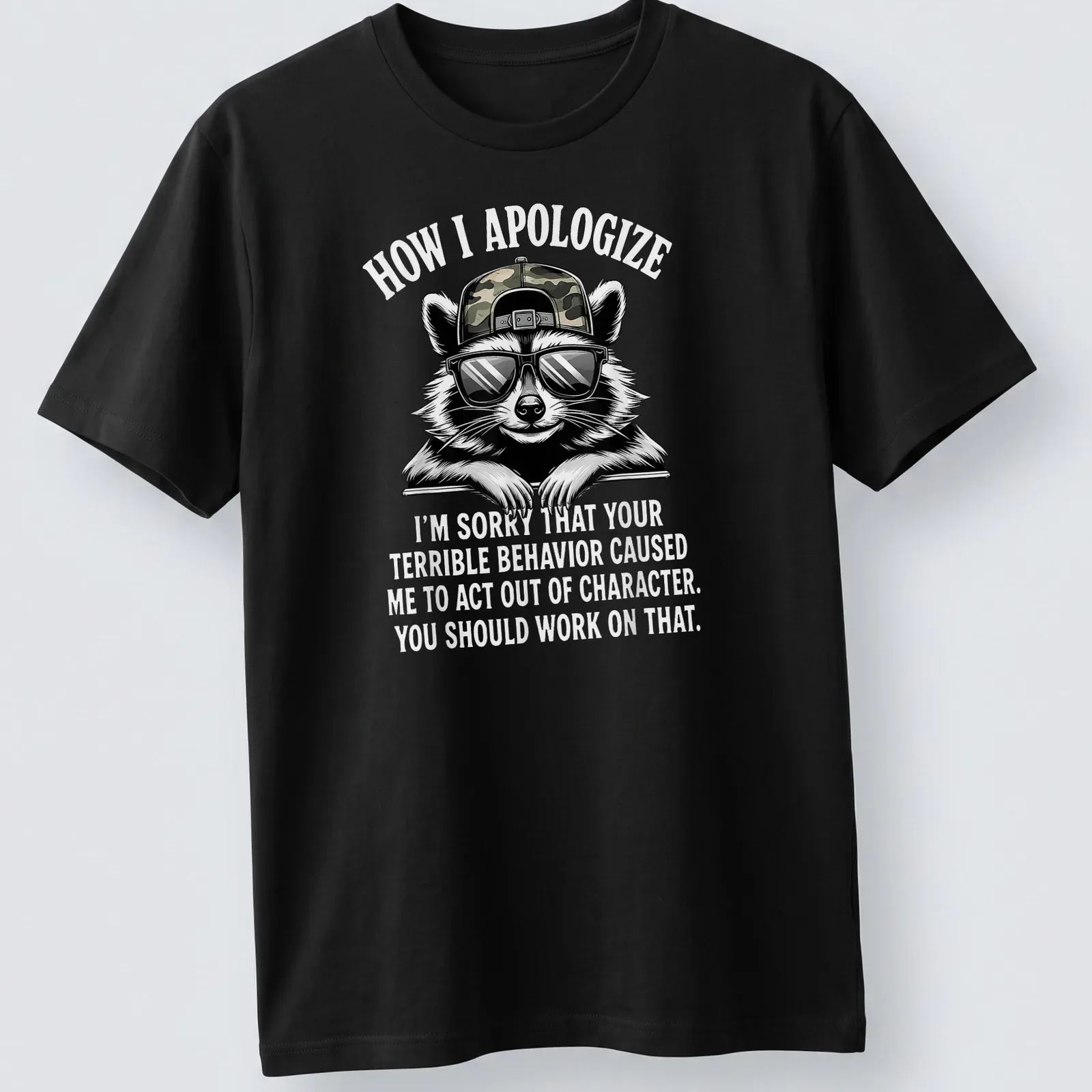 Bold cartoon print featuring a raccoon and humorous apology text — printed on a unisex t-shirt