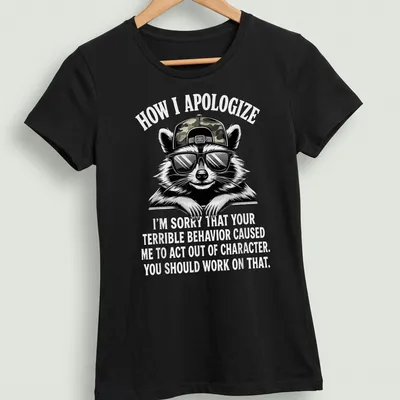 Bold cartoon print featuring a raccoon and humorous apology text — printed on a women's shirt