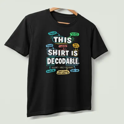 Decodable shirt for teachers, featuring colorful text promoting literacy — printed on a unisex t-shirt (angled view)
