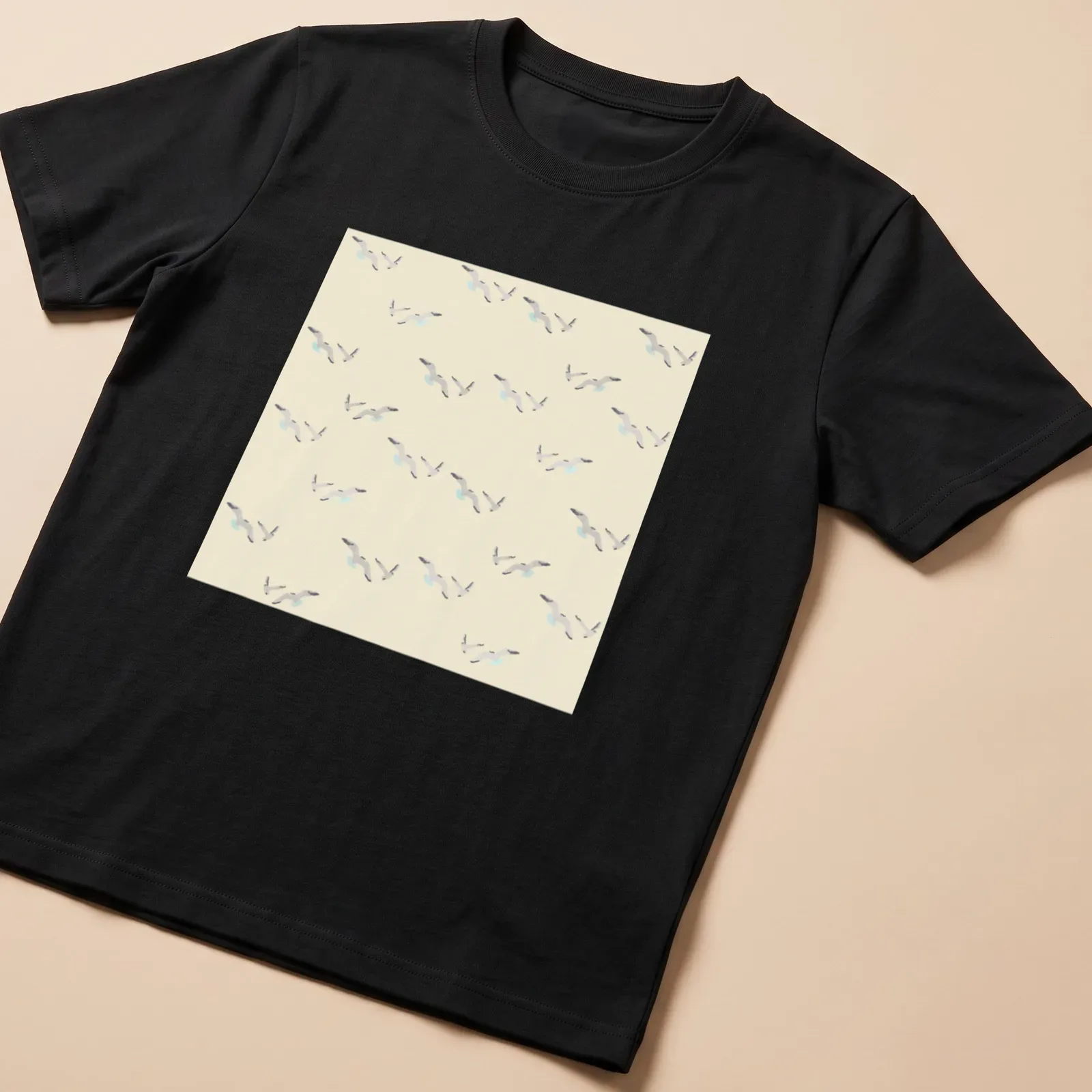 Watercolor design of seagulls in light beige and gray against a light blue background. — printed on a unisex t-shirt