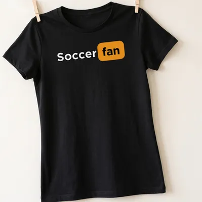 Bold modern typography shirt featuring the words Soccer Fan in black, orange, and white. — printed on a women's shirt
