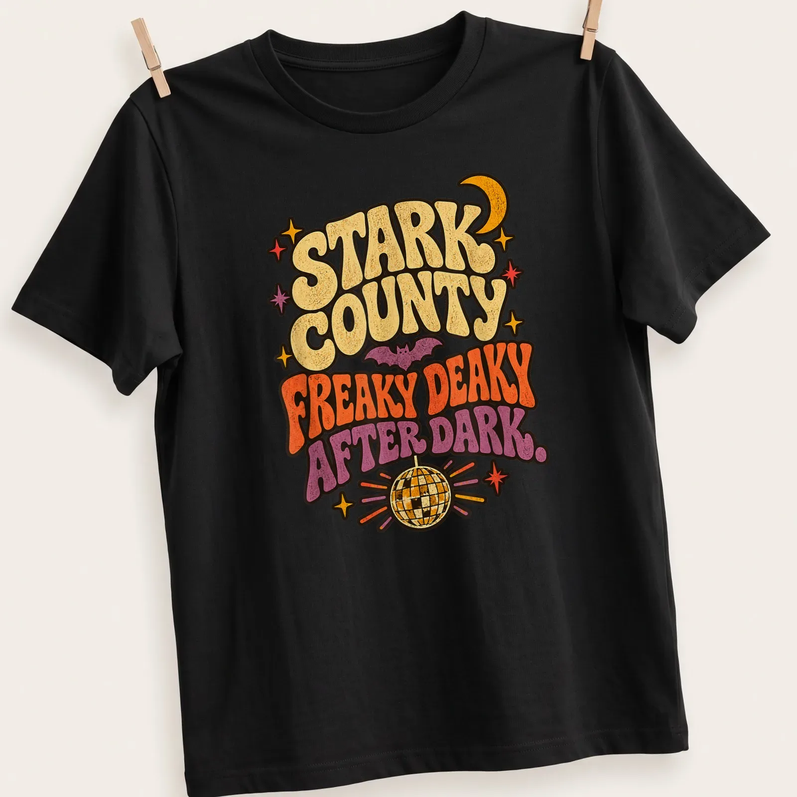 Retro design of a bat under a disco ball with vibrant colors and playful text. — printed on a unisex t-shirt
