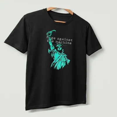 Vintage-style tee featuring the Statue of Liberty with Rage Against the Machine text in turquoise and black — printed on a unisex t-shirt (angled view)