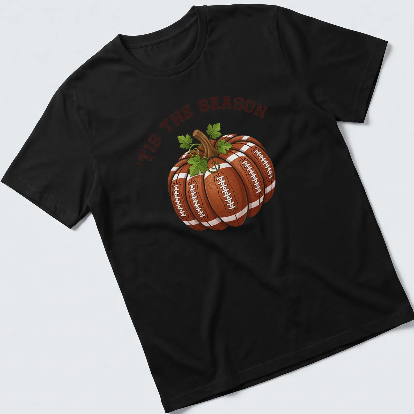 Cartoon pumpkin with footballs and the text 'TIS THE SEASON' in festive colors — printed on a unisex t-shirt