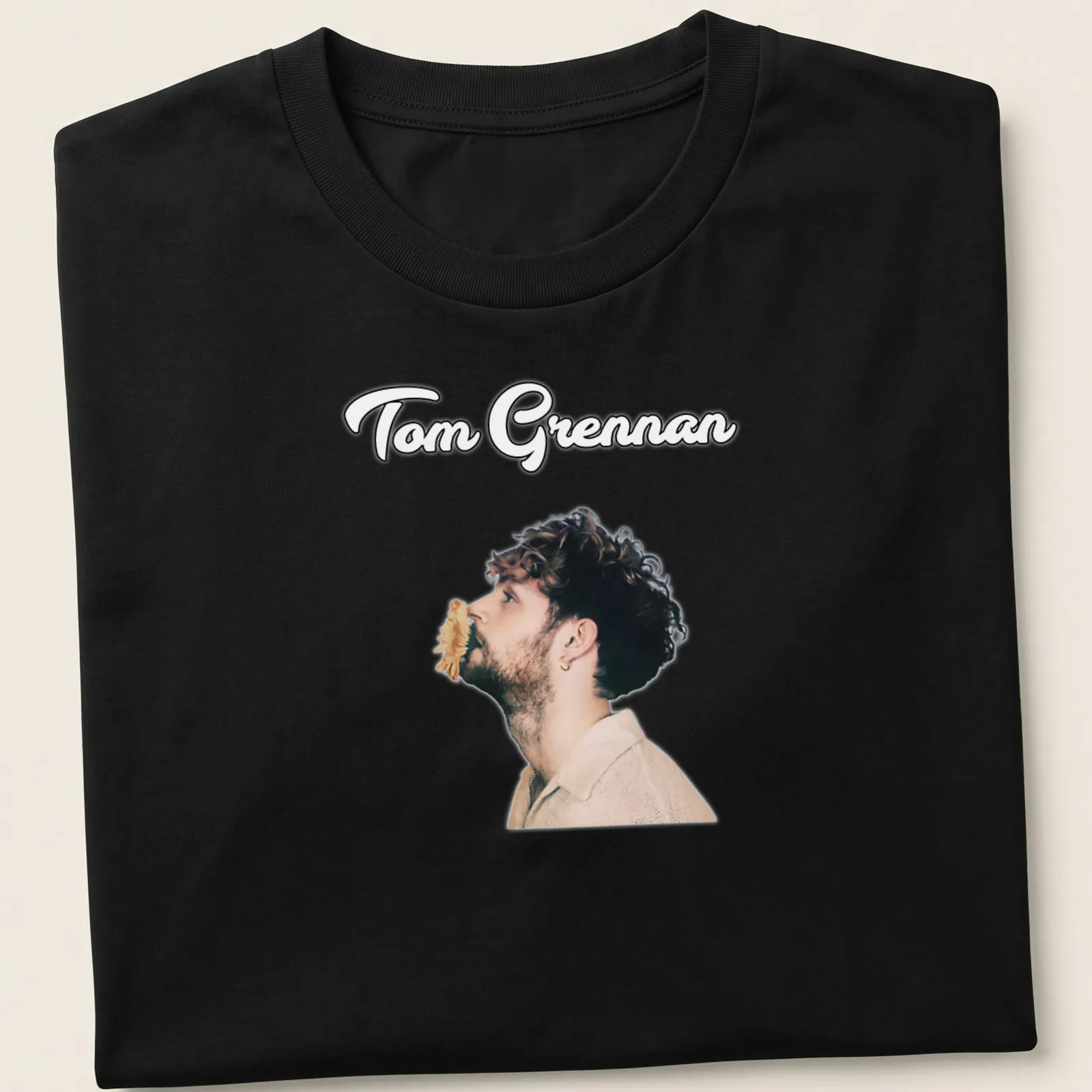 Illustration of Tom Grennan in modern portrait style with text in black, beige, and brown. — printed on a unisex t-shirt